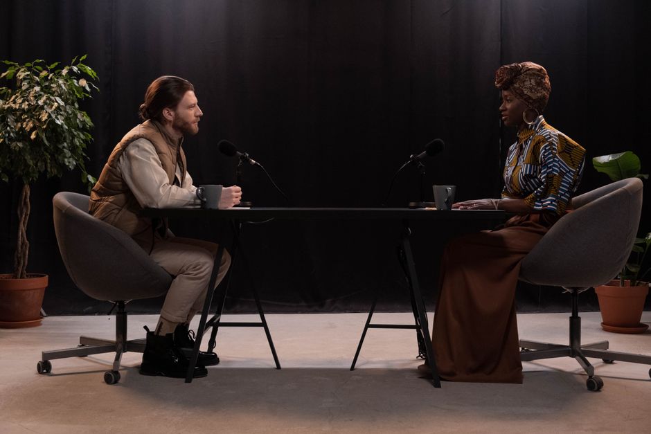 Two individuals having an engaging conversation in a studio setting with microphones.