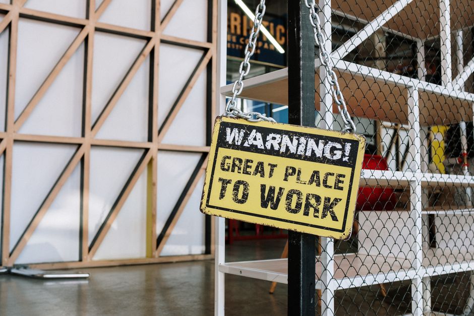 Humorous warning sign in a modern industrial loft workspace, capturing a blend of creativity and humor.